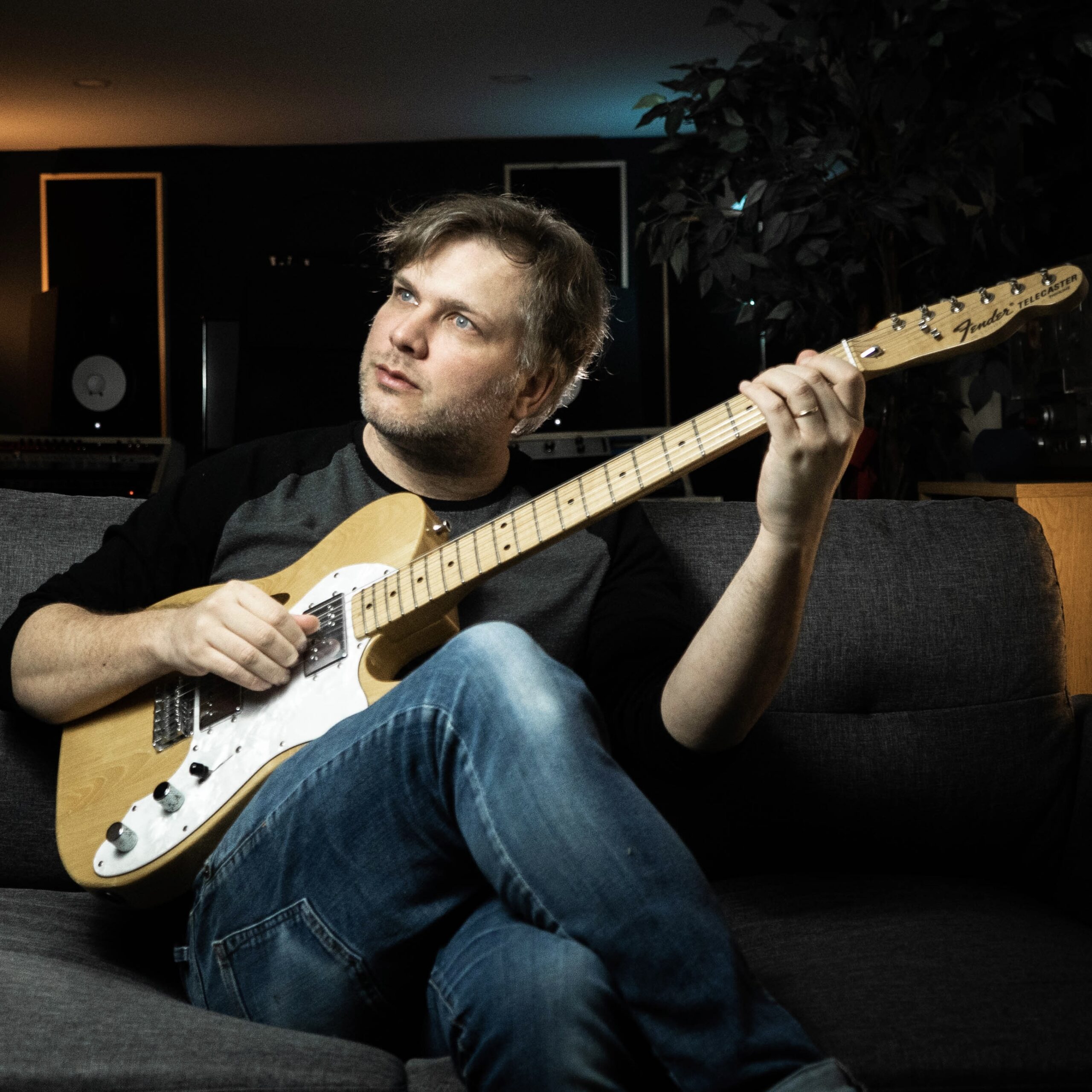 Playing guitar on a couch in a studio